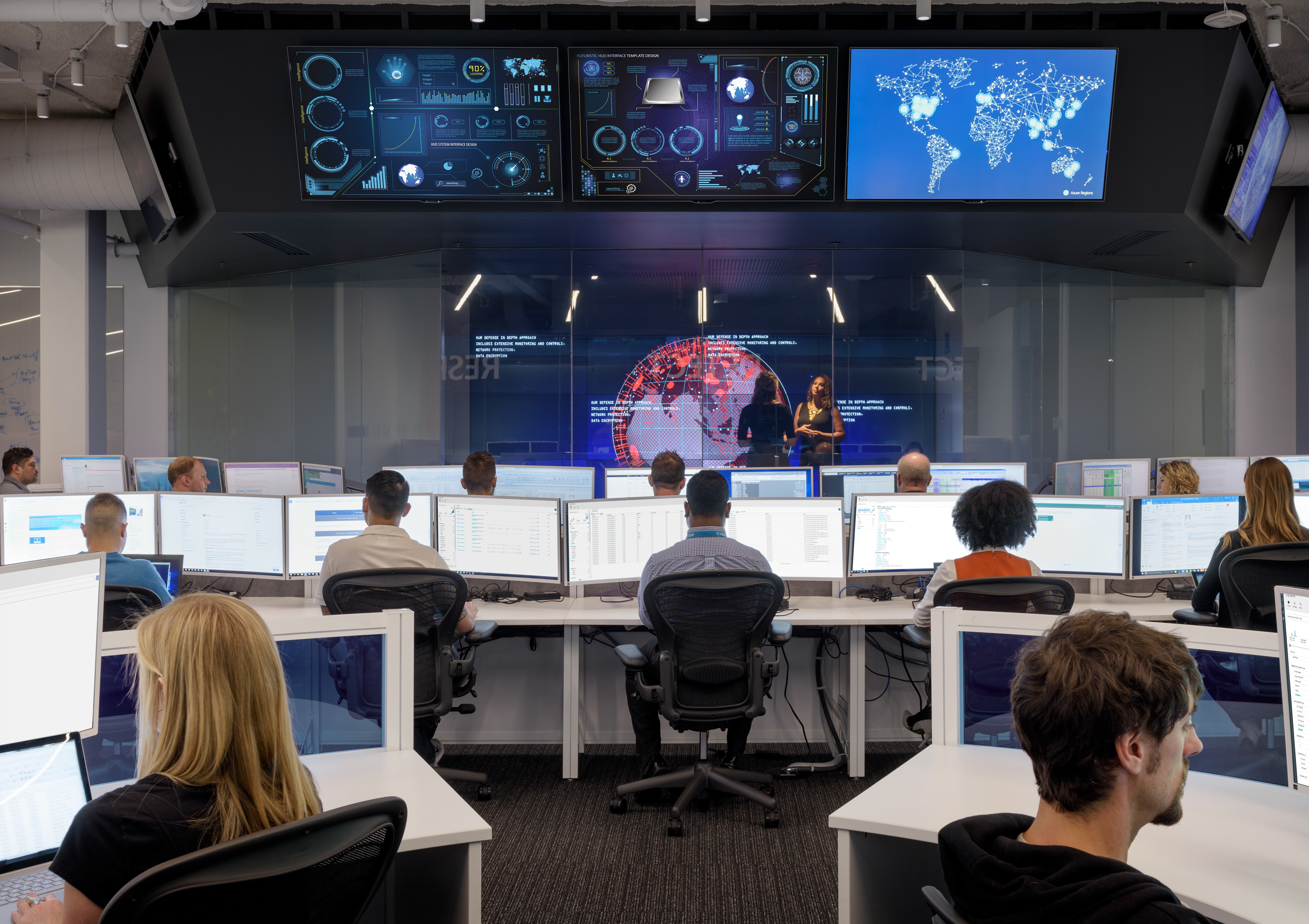 Several people in a large room, each in front of computer screens