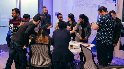 A group of teammates gather around a conference table