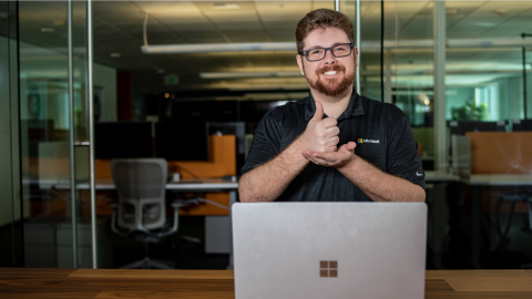 Image of a person standing in front of a laptop signing in ASL.