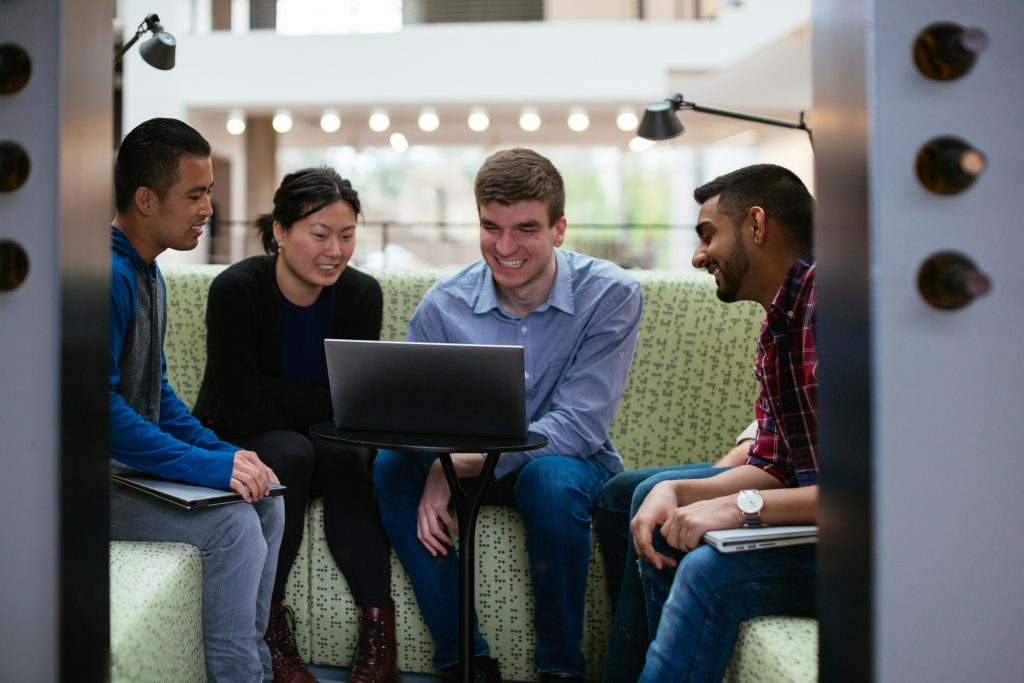 Alt text provided by Brand Central is: Bernardo Villarreal, a man who has low vision, sits with a group at an office building and they all look at his laptop screen.