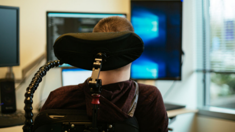 Chris Schlechty, a man who uses a wheelchair, looks at multiple monitors on his desk