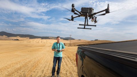 A man holds a tablet showing a multispectral image of a field.