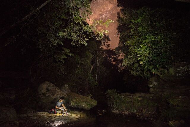 Camper sitting at creek with night sky above