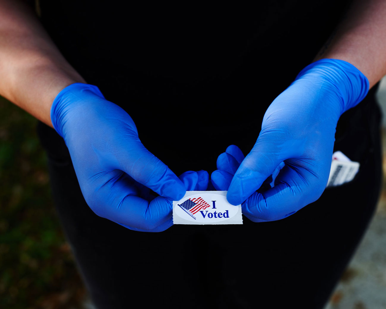 gloved hands holding I Voted sticker