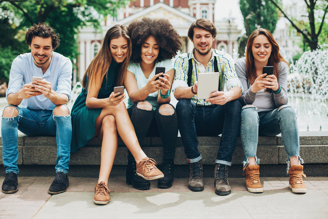 a diverse group of young people check their phones